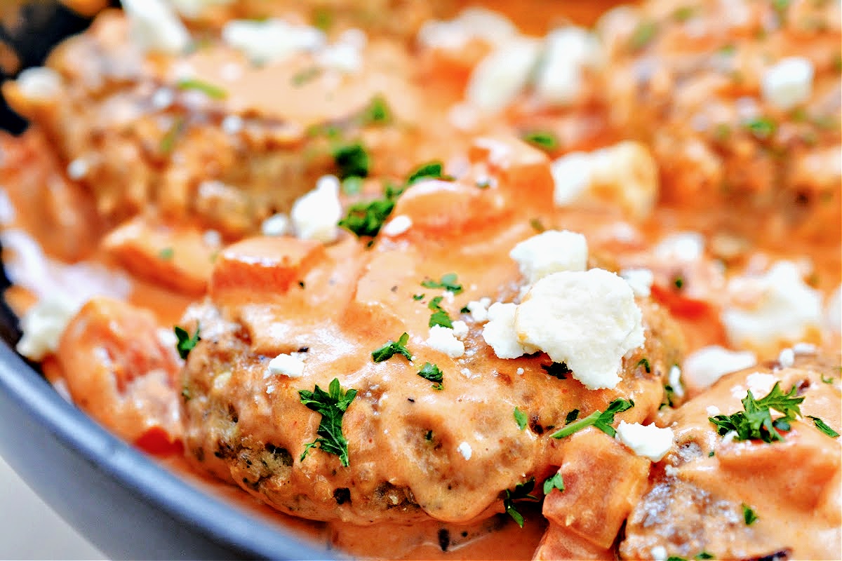 A close-up of salmon burgers covered in tomato sauce