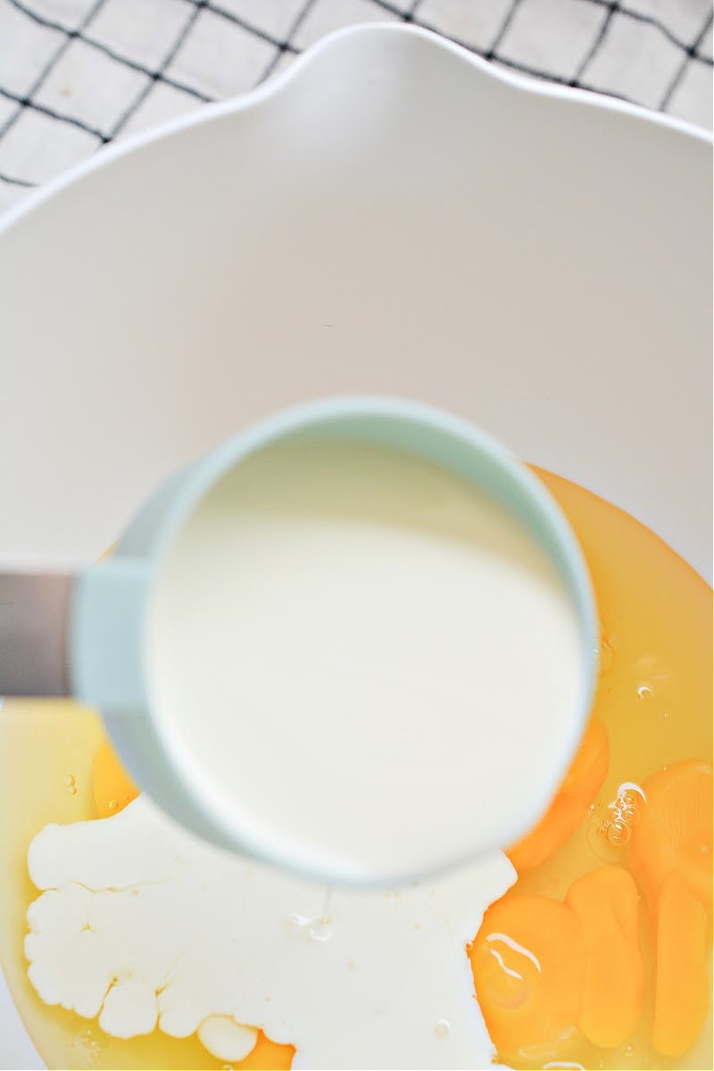 Mixing heavy cream with the eggs in a mixing bowl