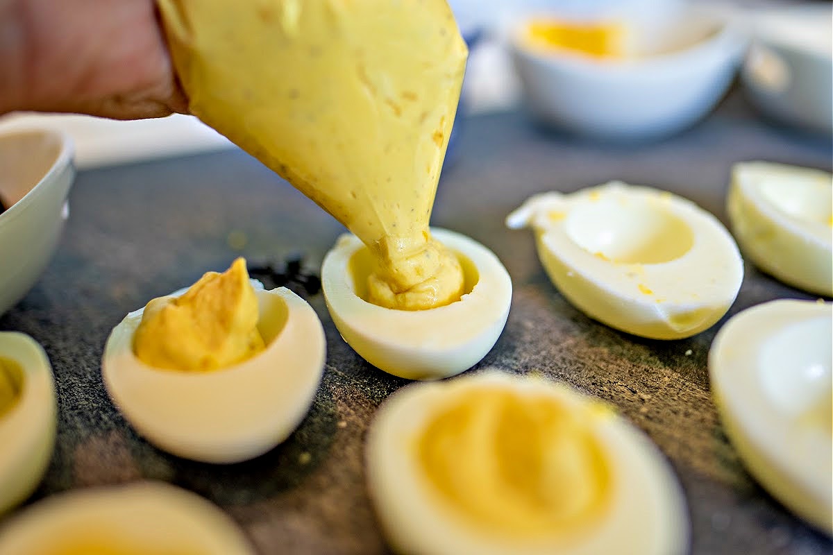 Piping egg yolks into egg whites for deviled eggs