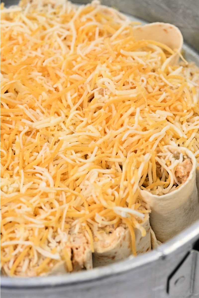Adding shredded cheese on top of the tacos